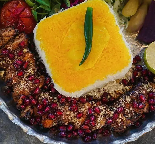 تصویری دلنشین از کباب مرغ آبدار رستوران شالِت، همراه با برنج زعفرانی معطر، دانههای انار و سبزیجات تازه.