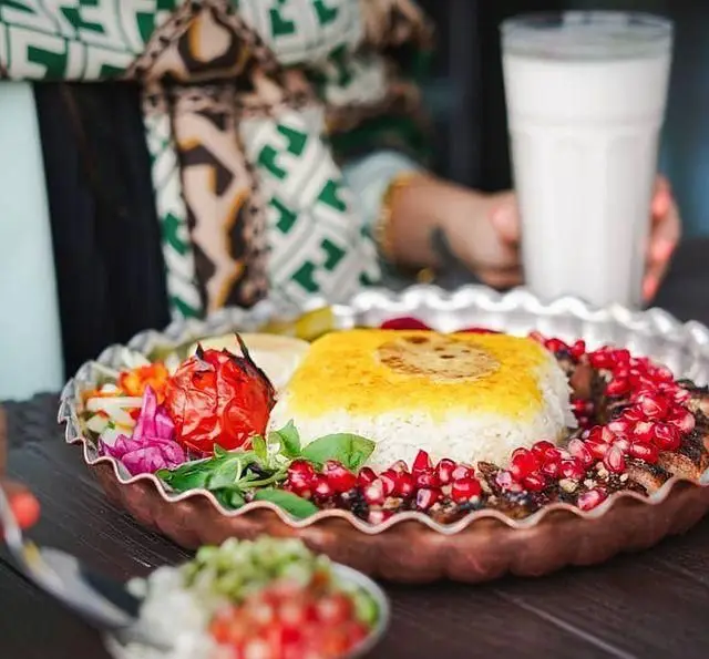 غذای اصیل ایرانی در رستوران شالت: برنج زعفرانی با ته دیگ طلایی، کباب اناری، گوجه کبابی و سبزیجات تازه. تجربهای لذیذ و دلنشین.