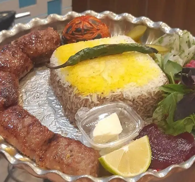 کباب کوبیده و پلو زعفرانی خوشطعم در رستوران شالِت. غذای اصیل ایرانی با گوجه کبابی، لیمو و کره. بهترین انتخاب برای یک وعده غذایی لذیذ.