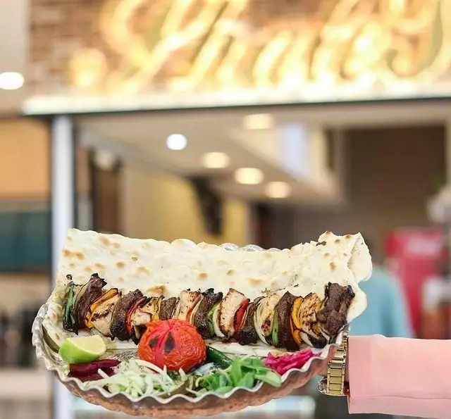بشقاب زیبای کباب میکس رستوران شالِت با گوشت و سبزیجات، نان داغ، گوجه کبابی و سبزیجات تازه.