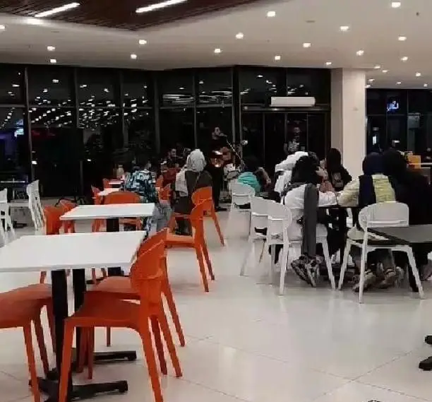 نمای داخلی رستوران شالِت، فضایی مدرن و دنج با مشتریانی که شبهنگام دور میزهای سفید و صندلیهای نارنجی و سفید جمع شدهاند. موسیقی زنده در حال اجراست.
