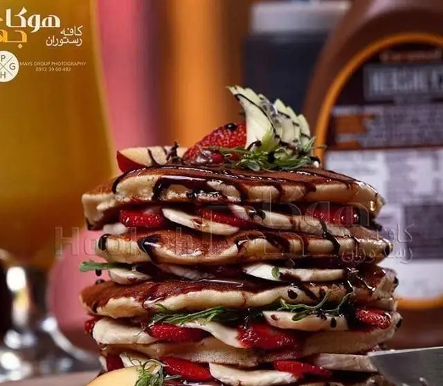 پنکیک‌های لذیذ و دلنشین کافه هوکاجی: یک برج بلند از پنکیک تازه با توت فرنگی، موز، سس شکلات. بهترین انتخاب برای دسر یا صبحانه خاص.