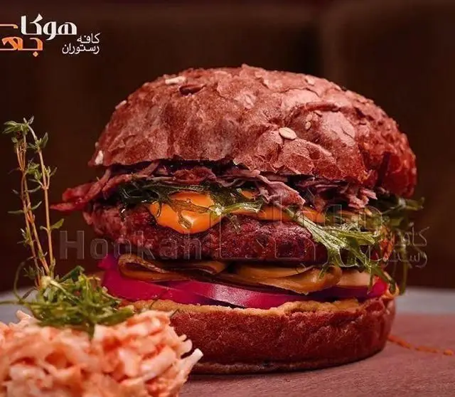 همبرگر ویژه کافه هوکاجی با نان چغندر، پنیر، بیکن و سالاد کلم؛ یک غذای خوشمزه از منوی رستوران هوکاجی.