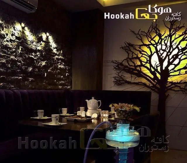 نمایی از کافه هوکاجی: فضای داخلی شیک و مدرن با نورپردازی گرم، میزهای آماده چای، دسر و قلیان برای دورهمی‌های دوستانه.