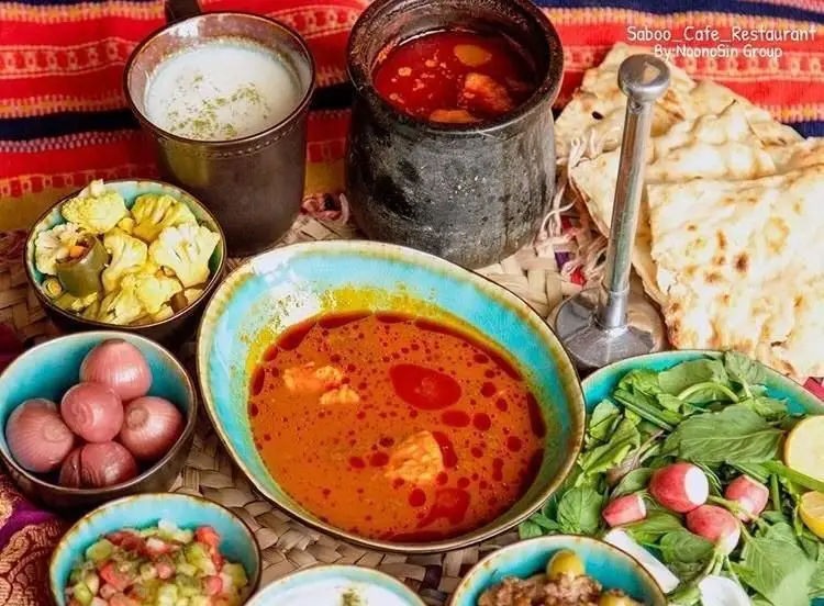 میز غذای سنتی و اصیل ایرانی در رستوران کافی شاپ سبو با آبگوشت، دوغ، نان تازه، انواع ترشی، سبزی خوردن و سالاد محلی.