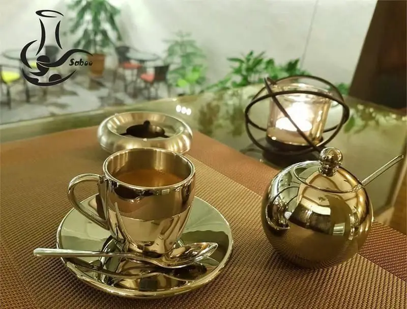 فضای داخلی دلنشین کافی شاپ سبو با میز براق و فنجان قهوه طلایی، قندان کروی و جاشمعی زیبا، محیطی لوکس برای مشتریان.