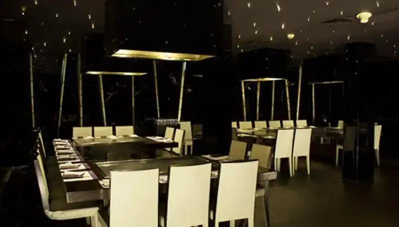 فضای داخلی لوکس رستوران کنزو با طراحی مدرن، میزهای گروهی تپپانیاکی و سقف نورانی ستاره‌ای. تجربه‌ای خاص برای شام.