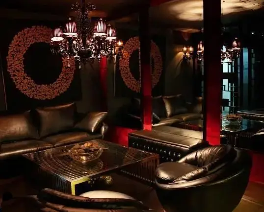 دکوراسیون داخلی لوکس و مدرن رستوران کنزو، شامل مبلمان چرمی تیره، لوستر کریستالی، میز قهوه شیشه‌ای و آینه‌های بزرگ در محیطی شیک و دلنشین.