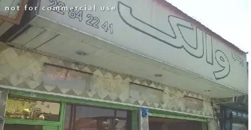 نمای بیرونی تابلوی مغازه "والک پیتزا" با حروف درشت فارسی و شماره تماس 22842241. یک رستوران فست فود در فضای شهری.