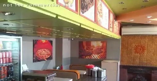 نمای داخلی رستوران والک پیتزا، شامل دکوراسیون جذاب با تابلوهای پیتزا و کباب، پیشخوان سرو و یخچال نوشیدنی.