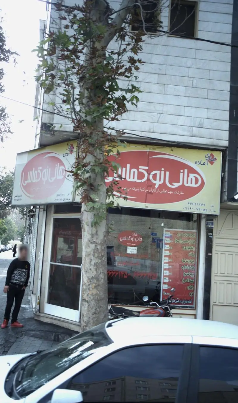 هانی نو کماسی: نمای بیرونی فروشگاه و مرکز تهیه غذای آماده و کترینگ با تابلو و منوی واضح. سفارشات پذیرفته می‌شود.