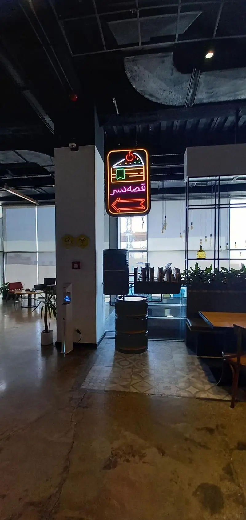 فضای دلپذیر داخلی رستوران مايا تِكس مِكس با تابلوی نئون "قصه دسر" و دکوراسیون مدرن کافه، محلی آرام برای جمع‌های دوستانه.