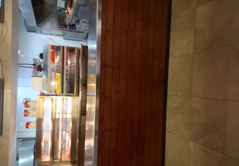 آشپزخانه صنعتی رستوران آواچی با تجهیزات استیل براق، هود قدرتمند و دستگاه‌های سرو غذای گرم مانند فرایر برای انواع فست فود.