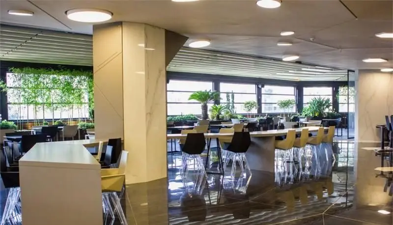 فضای داخلی مدرن و بزرگ فودکورت رویال تراس با میز و صندلی‌های متنوع، نورپردازی شیک و منظره فضای سبز بیرون.