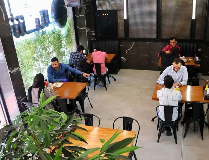 فضای داخلی مدرن فست فود شیلا با مشتریان مشغول صرف غذا، محیطی دنج و دوستانه برای تجربه بهترین طعم‌های فست فودی.