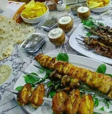 میز غذای ایرانی کامل از کباب‌های لذیذ شامل جوجه کباب و سایر کباب‌ها با نان داغ، چیپس و ماست، از کبابی چاشنی.