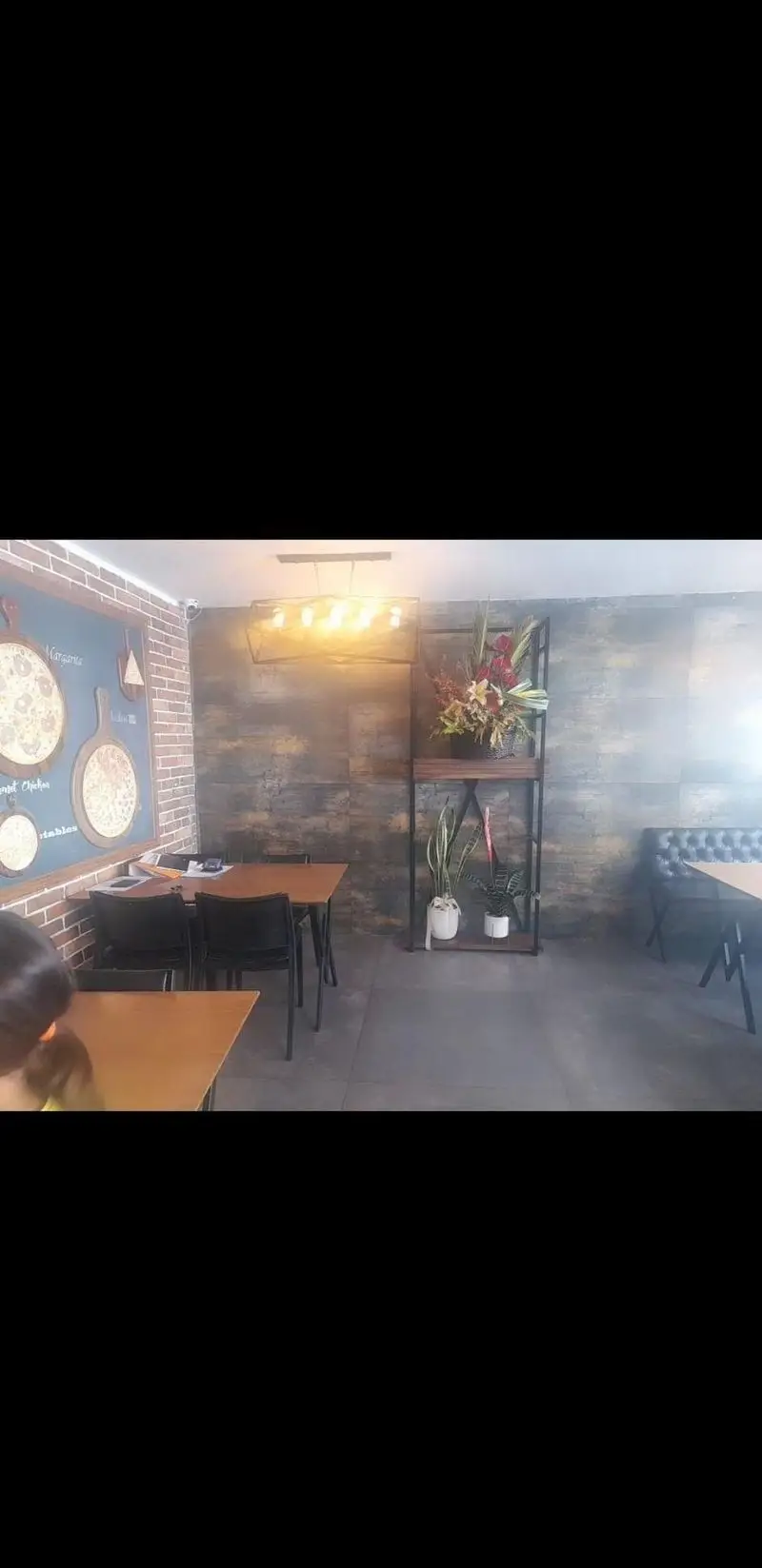 فضای داخلی شیک و مدرن فست فود زین با میز و صندلی، دیوار آجری، دکوراسیون پیتزا و محیطی دلنشین برای مشتریان.