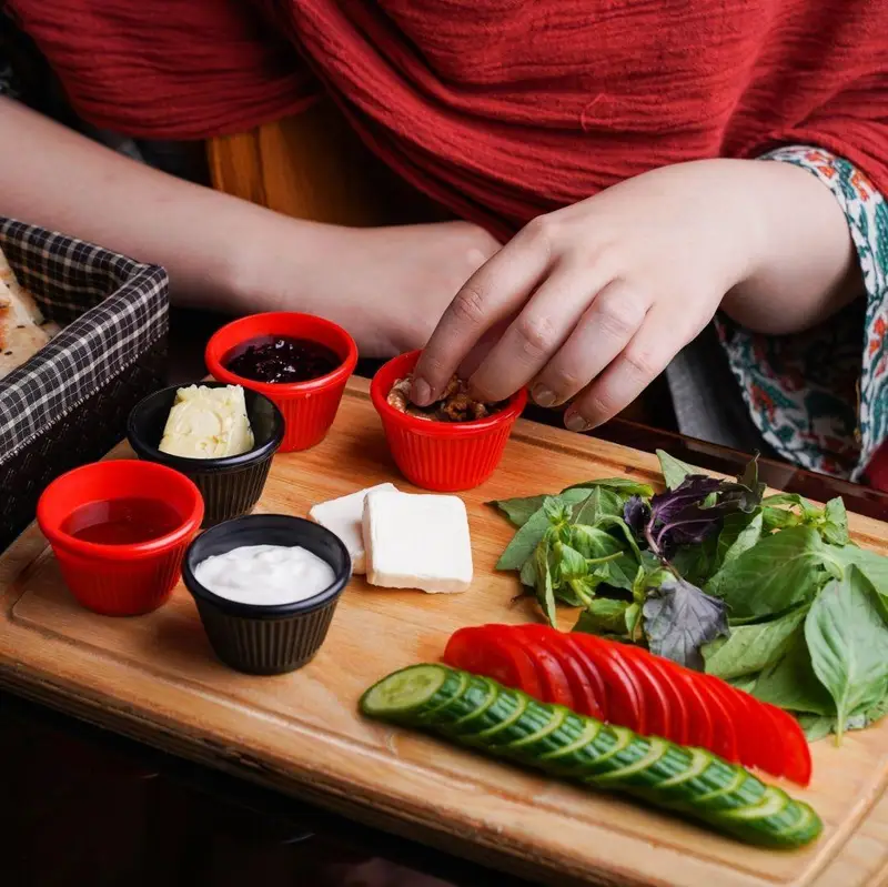 میز صبحانه سالم و کامل کافه رستوران عجمان شامل پنیر، کره، مربا، گردو، سبزیجات تازه، خیار و گوجه فرنگی، ایده‌آل برای برانچ.