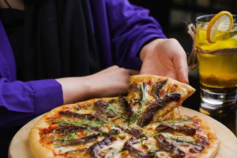 لذت خوردن پیتزای مخصوص گوشت و سبزیجات در کافه رستوران عجمان به همراه نوشیدنی گوارا برای یک تجربه فوق العاده