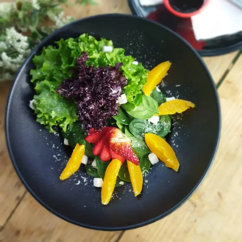 سالاد میوه‌ای و سبزیجات تازه کافه رستوران عجمان، با ترکیب جذاب کاهو، اسفناج، توت فرنگی، پرتقال و پنیر، یک گزینه سالم و پرانرژی برای مشتریان.