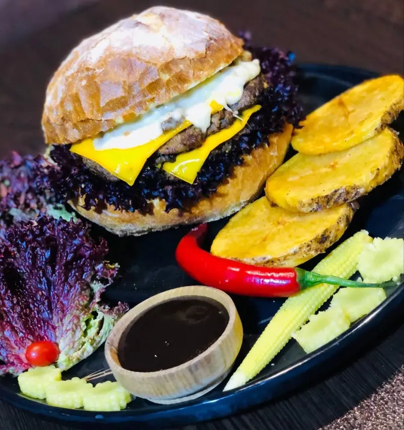 چیزبرگر دوبل ویژه کافه رستوران عجمان با پنیر، کاهو و سس، سرو شده با سیب‌زمینی برشته و سس مخصوص، مناسب ناهار و شام.