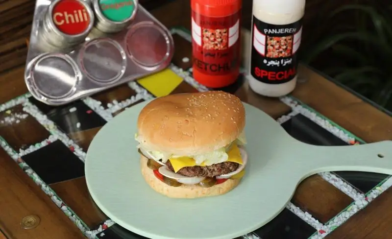 برگر لذیذ پیتزا پنجره با پنیر، کاهو، پیاز، گوجه و خیارشور، همراه با سس کچاپ و مایونز ویژه Panjereh Special.