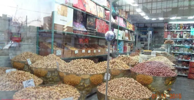 نمایی از ویترین پربار خشکبار بهمن، شامل انبوهی از پسته، بادام زمینی و انواع آجیل تازه و مرغوب آماده فروش در ظروف زیبا و بزرگ.