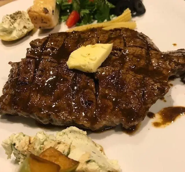 سفارش استیک لذیذ و پرطرفدار کافه رستوران مکث با سس مخصوص و کره، سرو شده با سالاد تازه، بیبی کورن و پوره.
