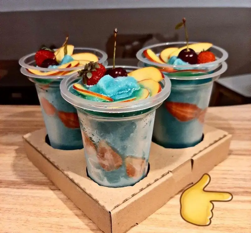 سه نوشیدنی اسموتی آبی رنگ و میوه‌ای کافه رستوران مکث | Maks با تکه‌های توت فرنگی، سیب و گیلاس، آماده سرو در کاریر.