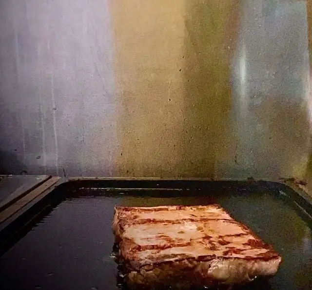 استیک گریل شده و آبدار در حال پخت روی سینی گریل داغ، غذای محبوب و تازه کافه رستوران مکث. آماده برای یک تجربه طعم لذیذ.