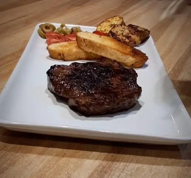 استیک لذیذ و مغزپخت گریل شده با نان سیر برشته، زیتون و گوجه فرنگی، غذای اصلی کافه رستوران مکث.