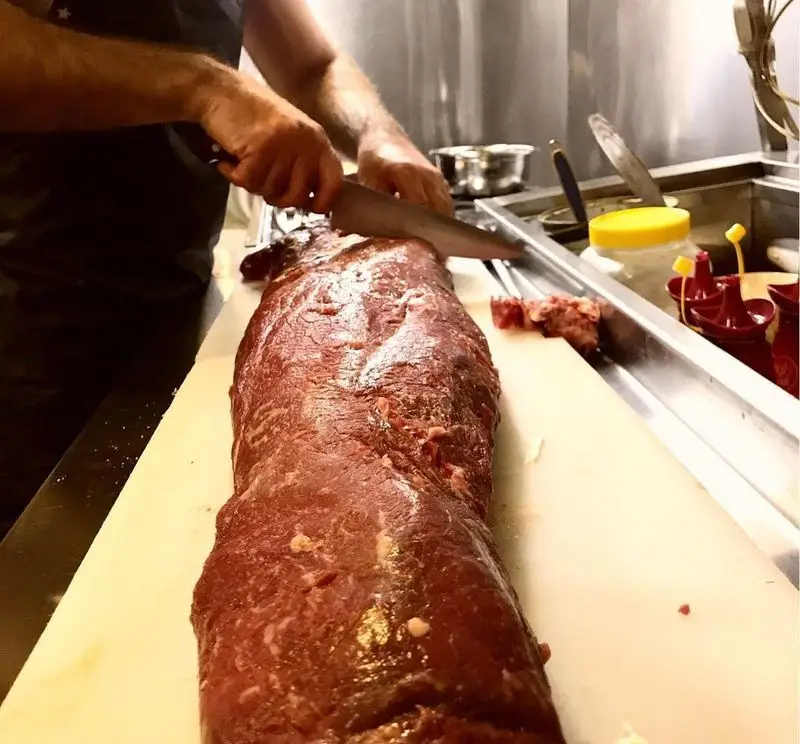 برش گوشت تازه و باکیفیت توسط آشپز حرفه‌ای کافه رستوران مکث در آشپزخانه مجهز. تضمین تازگی و طعم بی‌نظیر برای مشتریان.