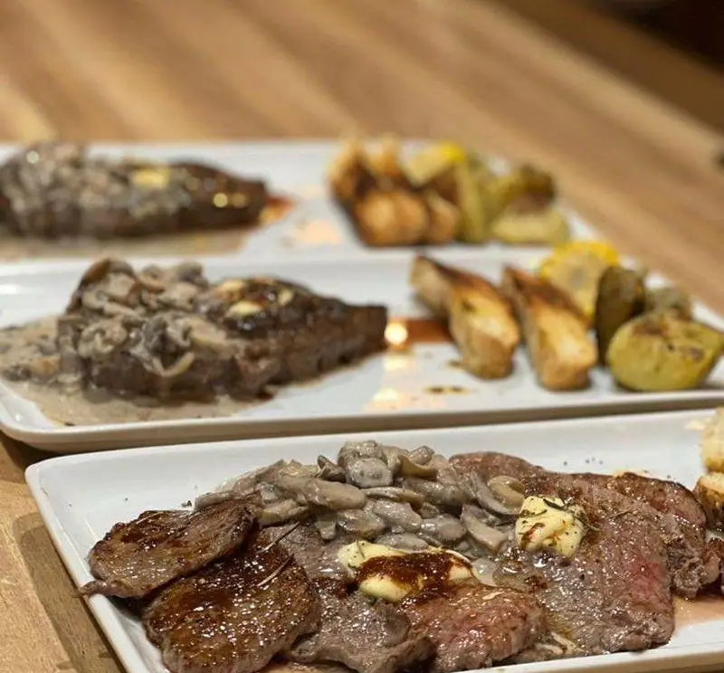 انواع استیک‌های ممتاز با سس قارچ، کره، نان تست و سبزیجات در کافه رستوران مکث. لذت یک وعده غذایی رویایی.