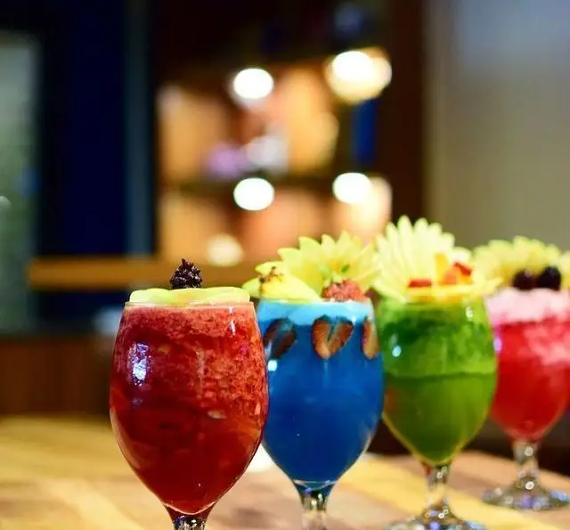 چهار نوشیدنی اسموتی و کوکتل میوه‌ای رنگارنگ و شاداب در کافه رستوران مکث. نوشیدنی‌های جذاب با تزئینات زیبا.