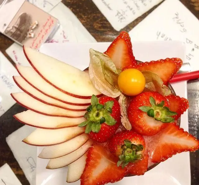 دسر میوه‌ای تازه و وسوسه‌انگیز با توت فرنگی، سیب ورقه شده و فیسالیس، با تزئینی زیبا، محصول کافه رستوران مکث.