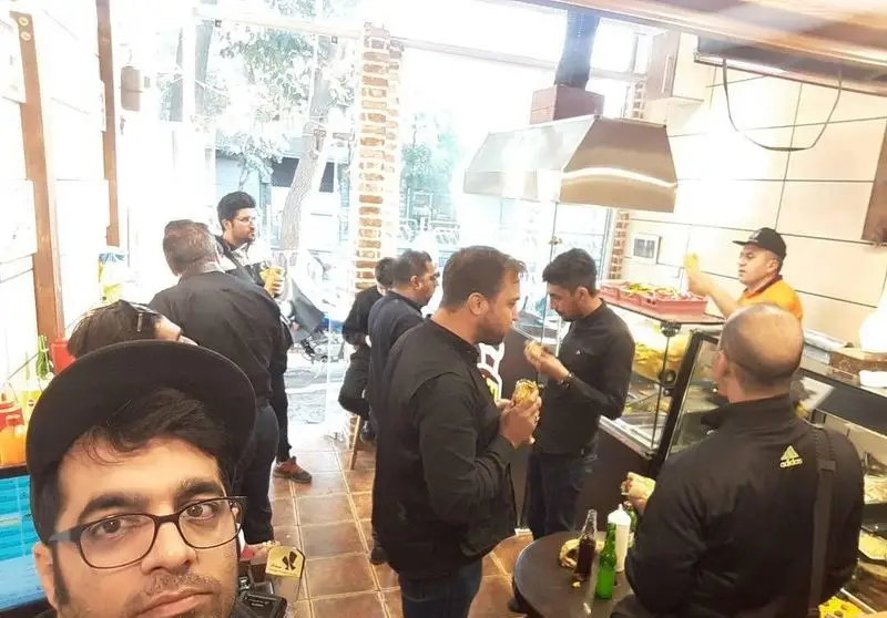 تصویری از مشتریان و فضای داخلی فست فود حمید و مجید در حال لذت بردن از غذاهای خوشمزه و ساندویچ‌ها.