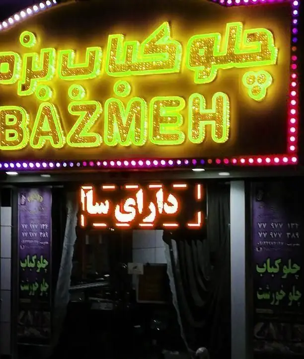 تابلوی درخشان رستوران چلوکباب بزمه (BAZMEH) در شب، با سرویس چلو کباب و چلو خورش و فضای سالن غذاخوری.