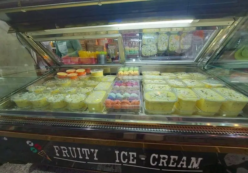 ویترین جذاب و پر از محصولات متنوع بستنی مسعود، شامل کاسه‌های بستنی میوه‌ای و دسرهای یخی آماده سرو.