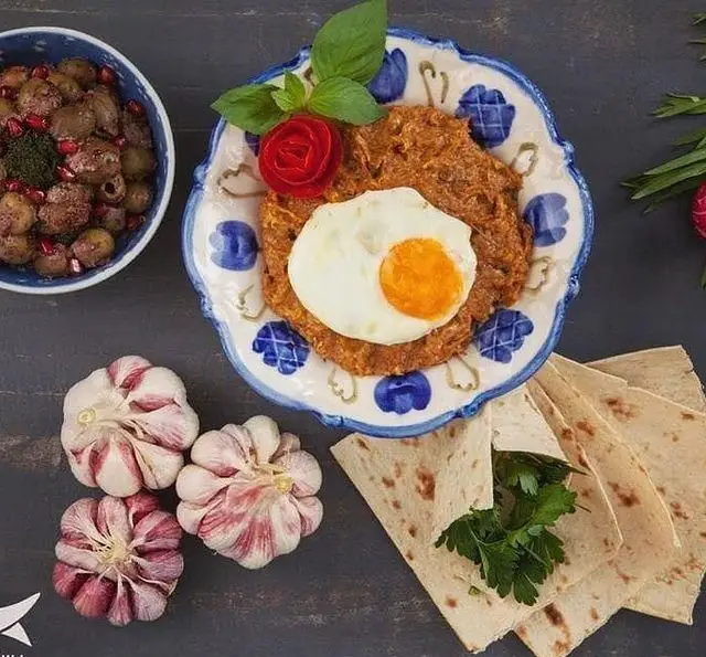 غذای سنتی و محلی رستوران ماهی سفید شامل خوراک دلچسب با تخم مرغ نیمرو، نان تازه، سیر و سیب زمینی؛ انتخابی عالی برای وعده ها.