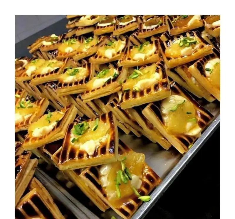 شیرینی سرای پدر: سینی بزرگ شیرینی‌های مربعی لذیذ با فیلینگ مربا، کرم و پسته. بهترین شیرینی تازه و سنتی ایرانی برای مناسبت‌ها.