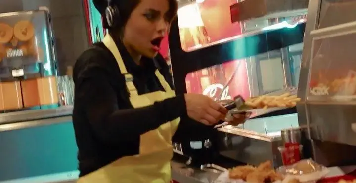کارمند جیکی بیف با هیجان در حال آماده سازی سفارش سیب زمینی سرخ کرده و مرغ سوخاری در محیط فعال و پویای رستوران فست فود.