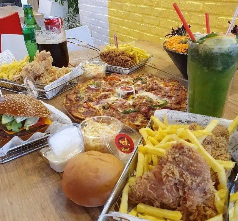 انواع فست فودهای لذیذ جیکی بیف شامل پیتزا، مرغ سوخاری ترد، همبرگر و سیب‌زمینی سرخ کرده در محیطی دلنشین.