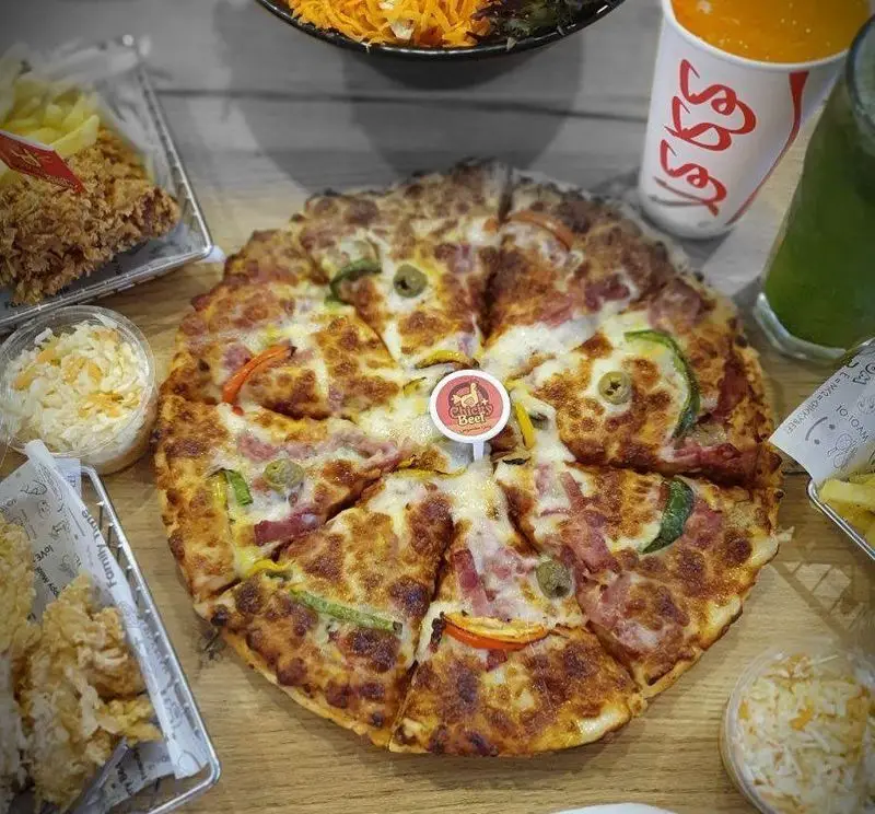 پیتزای بزرگ و وسوسه‌انگیز جیکی بیف با مخلفات متنوع، مرغ سوخاری، سیب‌زمینی، سالاد کلم و نوشیدنی‌های خنک برای یک وعده کامل و لذت‌بخش.