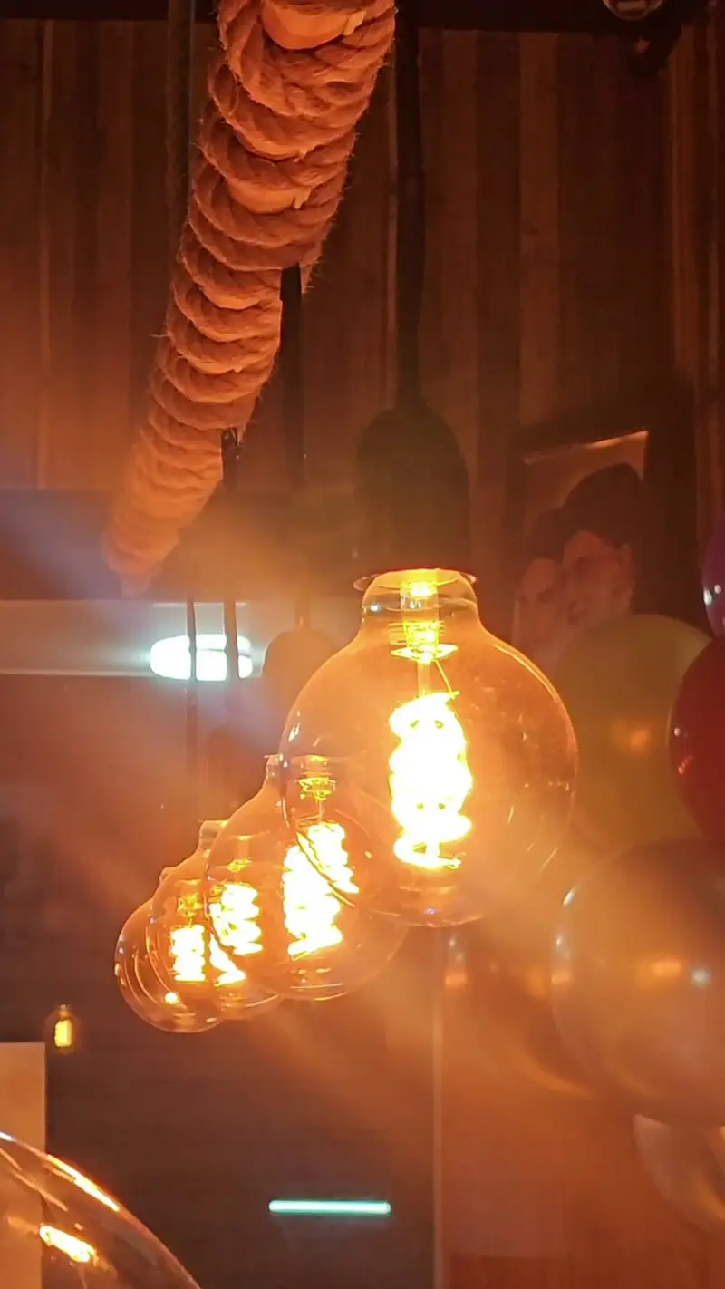 نمایی از نورپردازی زیبای کافه لوف با لامپ‌های رشته‌ای ادیسونی و طناب‌های تزئینی، فضایی گرم و مدرن برای تجربه‌ای لذت‌بخش.