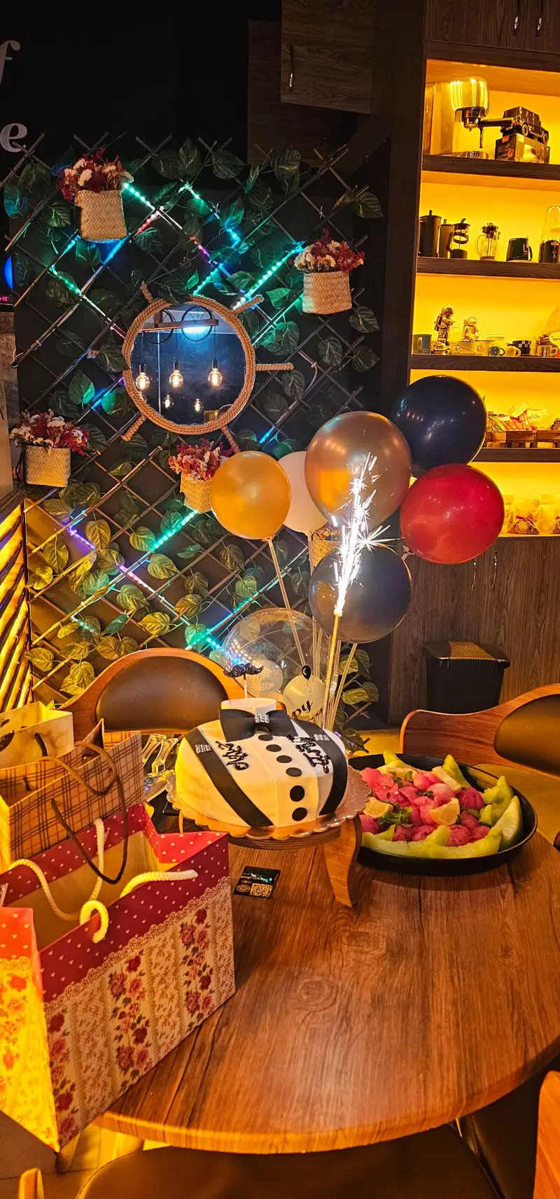 تصویری از جشن تولد در کافه لوف با کیک خاص مردانه، بادکنک‌های شاد، سینی میوه تازه و هدیه‌های جذاب. دکوراسیون دلنشین کافه.