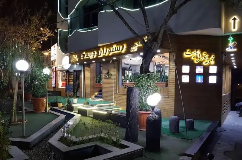 نمای شبانه رستوران و فست فود ویست فود با نورپردازی چشم‌نواز، فضای باز سرسبز و دکوراسیون مدرن و جذاب.