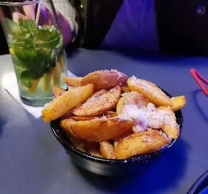 لذت تجربه سیب‌زمینی وج‌های طلایی و ترد با چاشنی پنیری در کافه رستوران الک دولک، به همراه نوشیدنی موهیتو خنک با لیمو و نعنا.