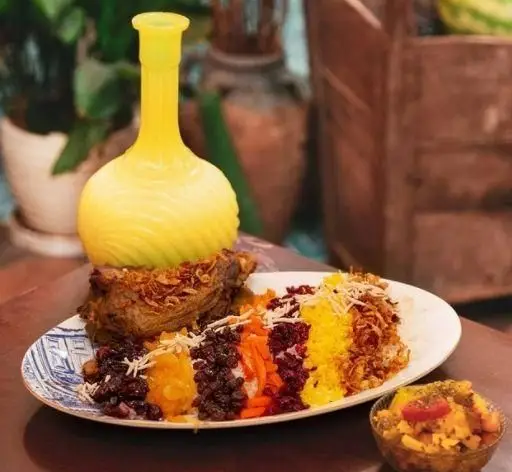 غذای اصیل ایرانی شامل پلو رنگارنگ با گوشت، برنج و مخلفات متنوع، در محیط دلنشین کافه رستوران وکیل التجار شیراز.