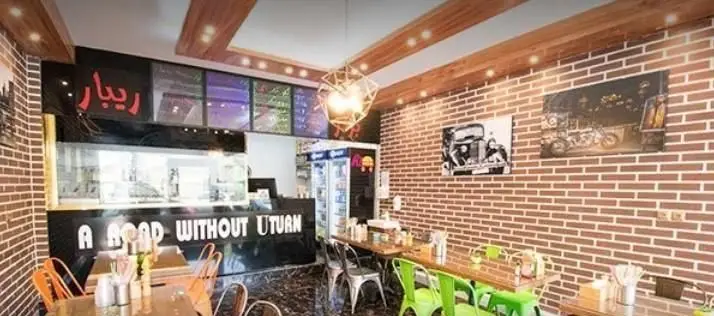 تصویری از داخل رستوران فست فود ریبار برگر با دیوارهای آجری، سقف چوبی و نورپردازی مدرن، فضایی گرم و دوستانه برای مشتریان.