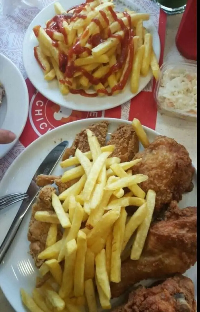 مرغ سوخاری دی: نمای نزدیک از وعده غذایی کامل با تکه‌های مرغ سوخاری ترد، سیب زمینی سرخ کرده فراوان و سس کچاپ